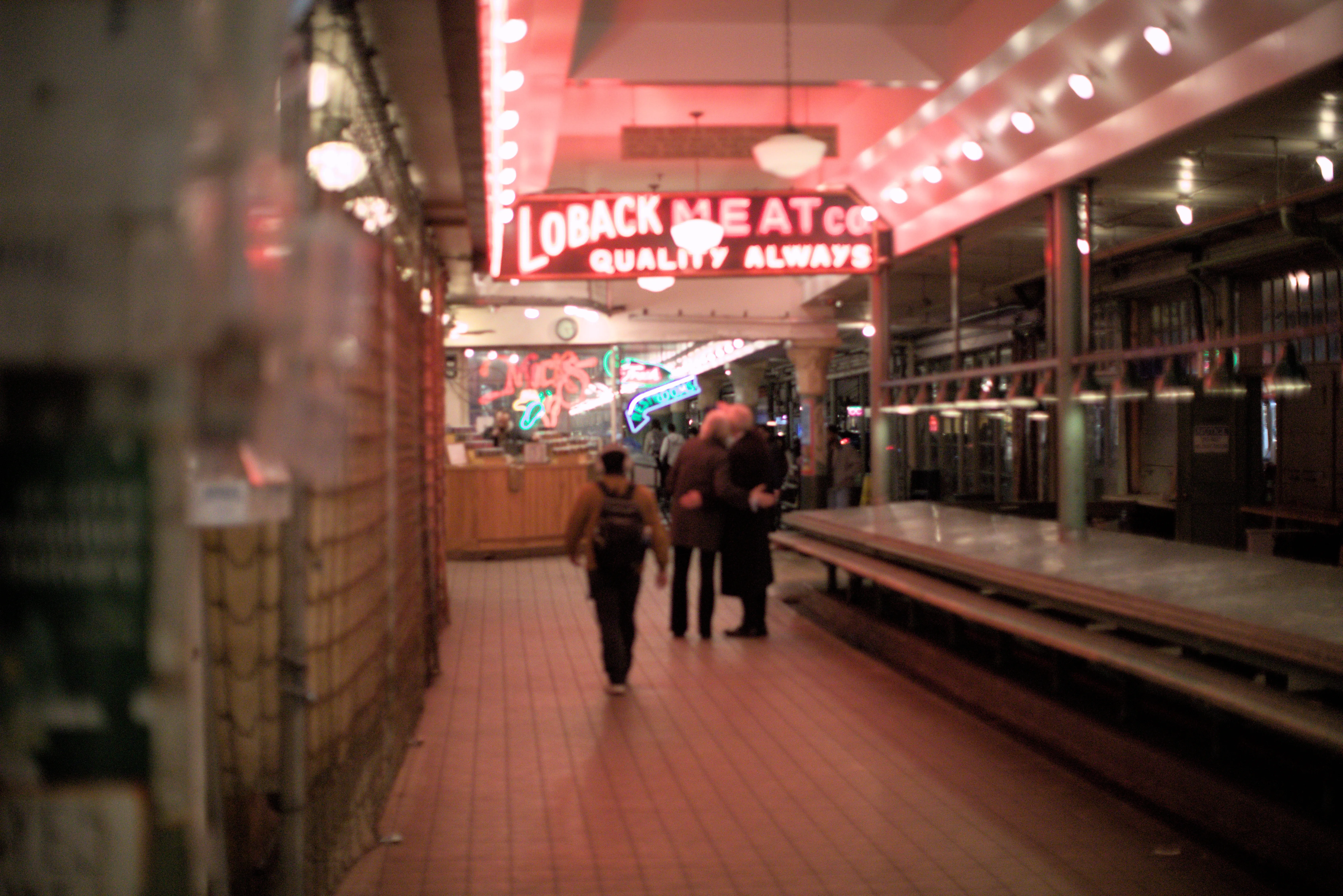 An elderly couple embrace in the neon lights of Pike Place Market