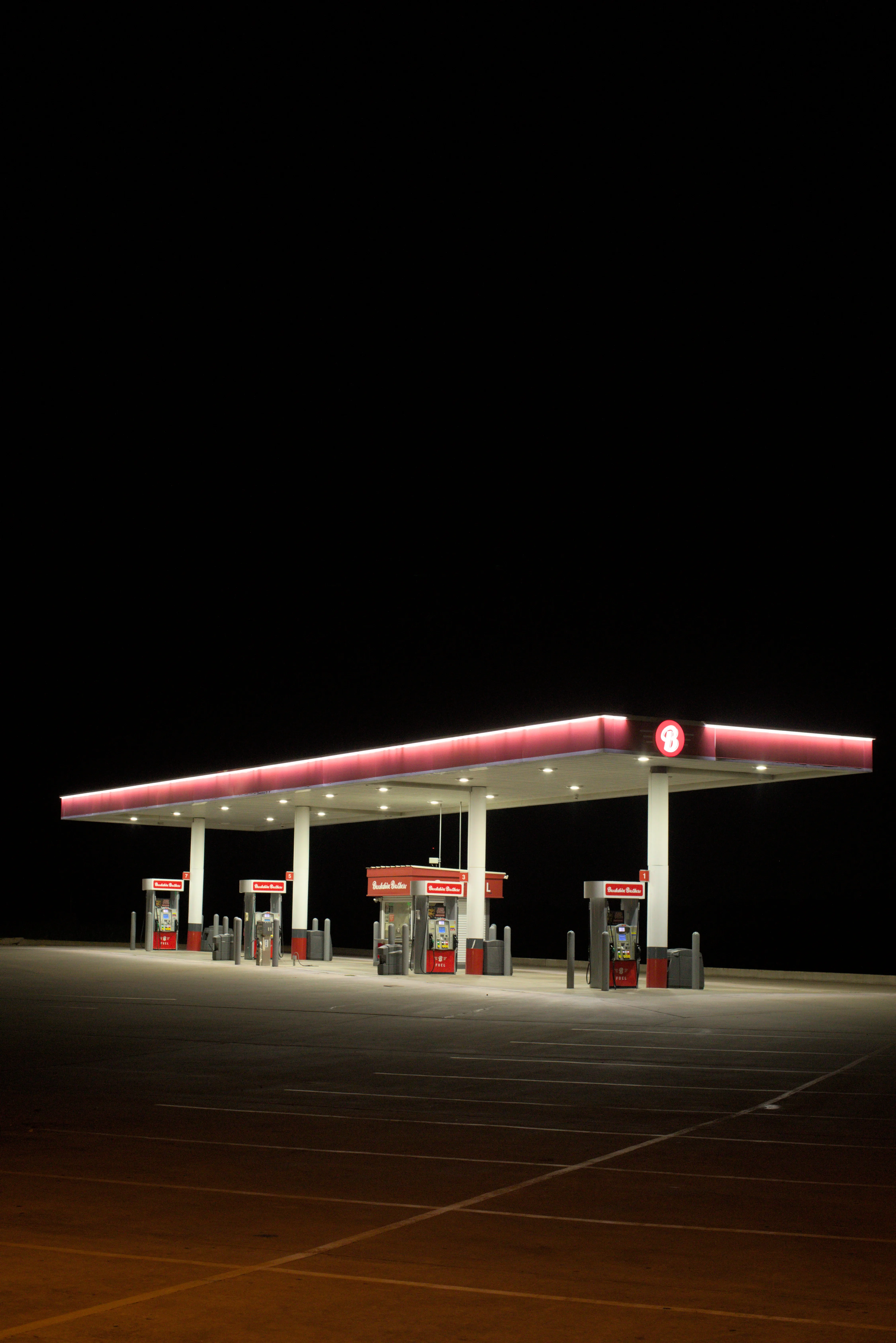 An empty gas station sits lit up in front of a black void