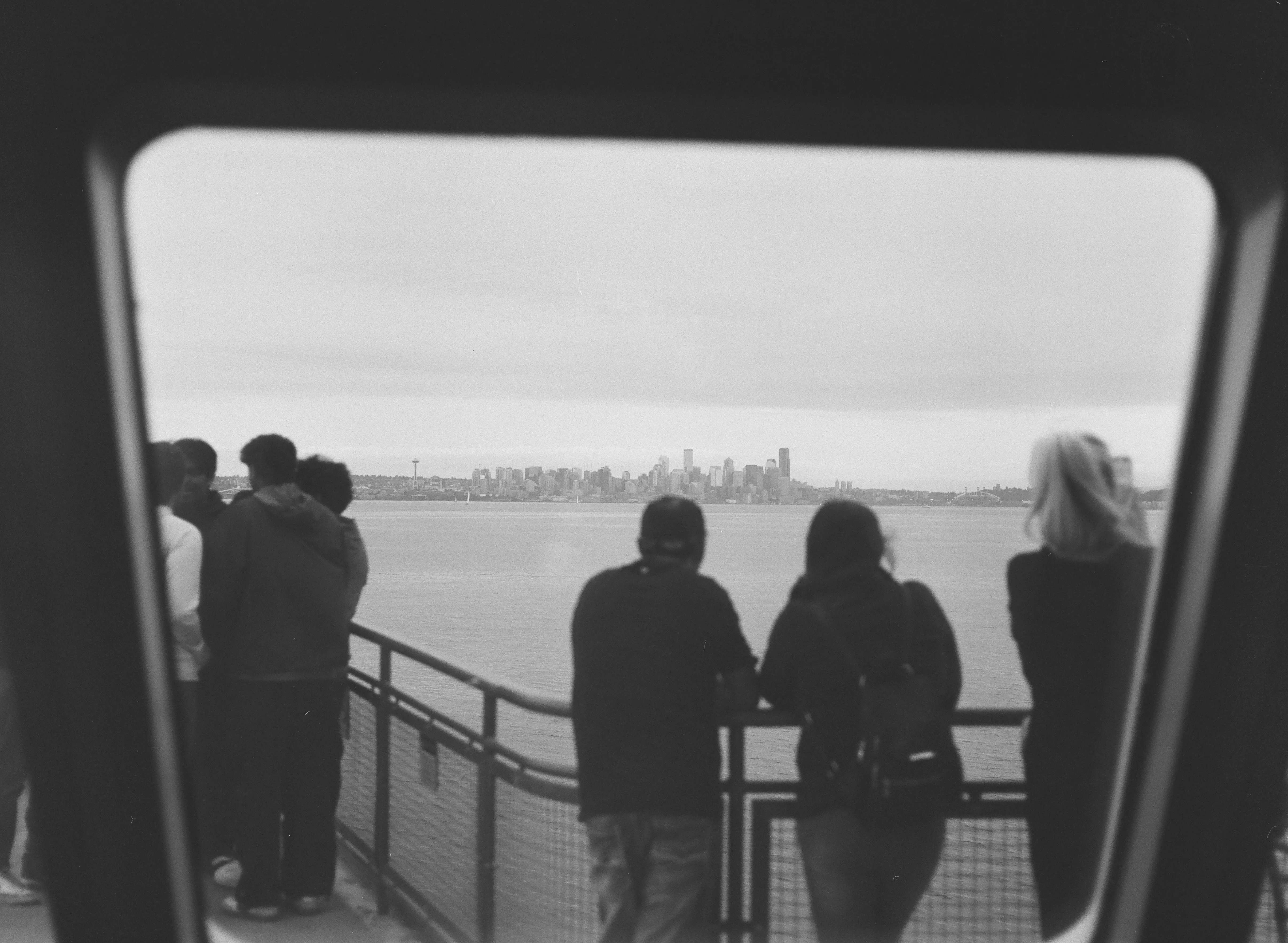 People standing on the deck of the Bainbridge ferry, looking to downtown Seattle