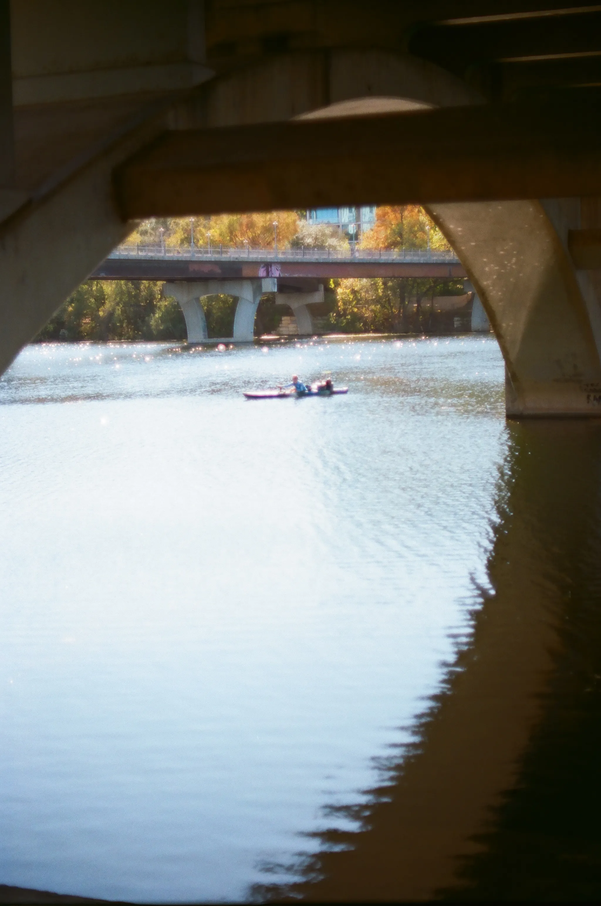 A lone kayaker is framed by the spans of the Lamar Bridge