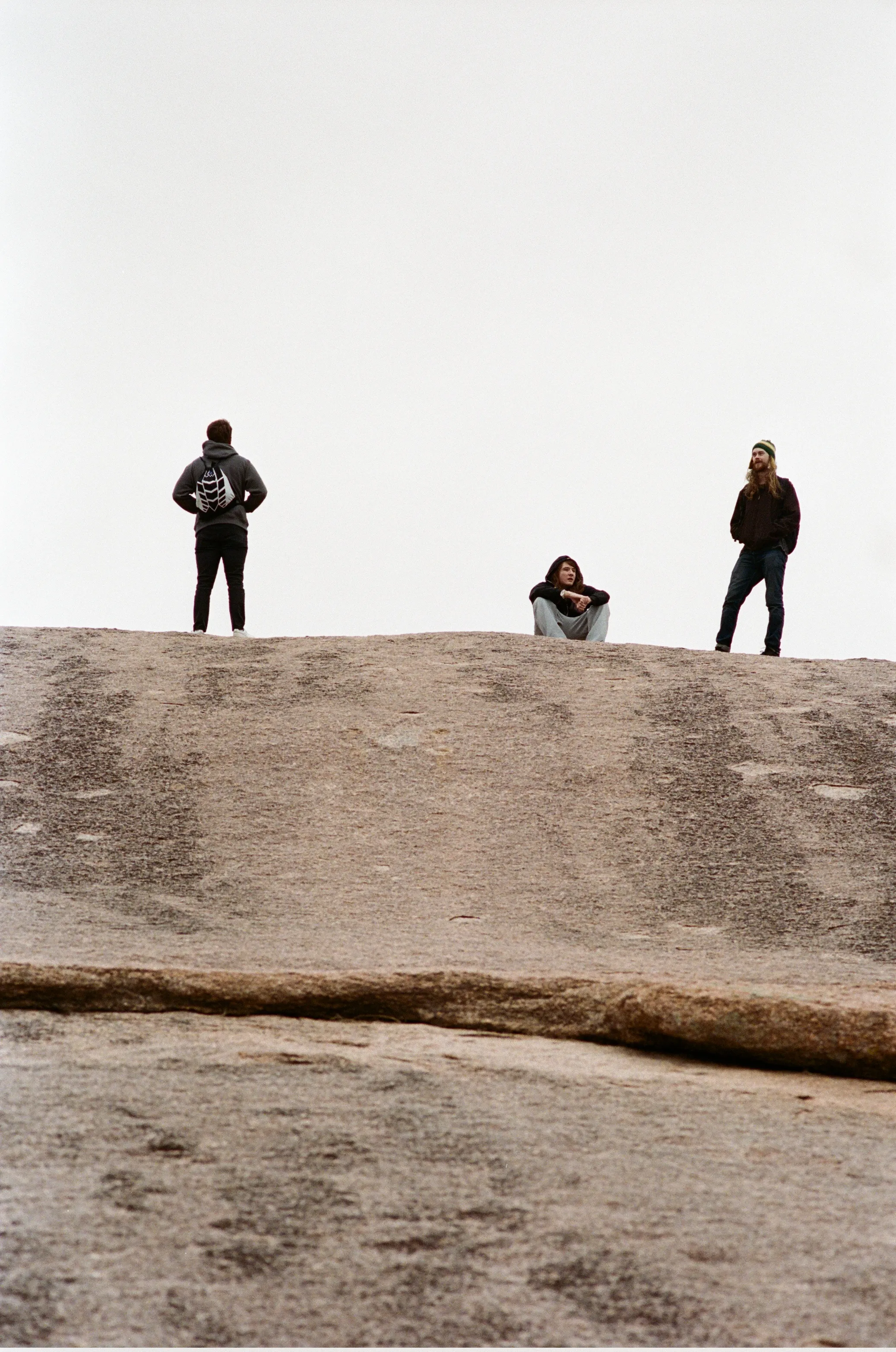 Three people standing atop Enchanted Rock, on an overcast day