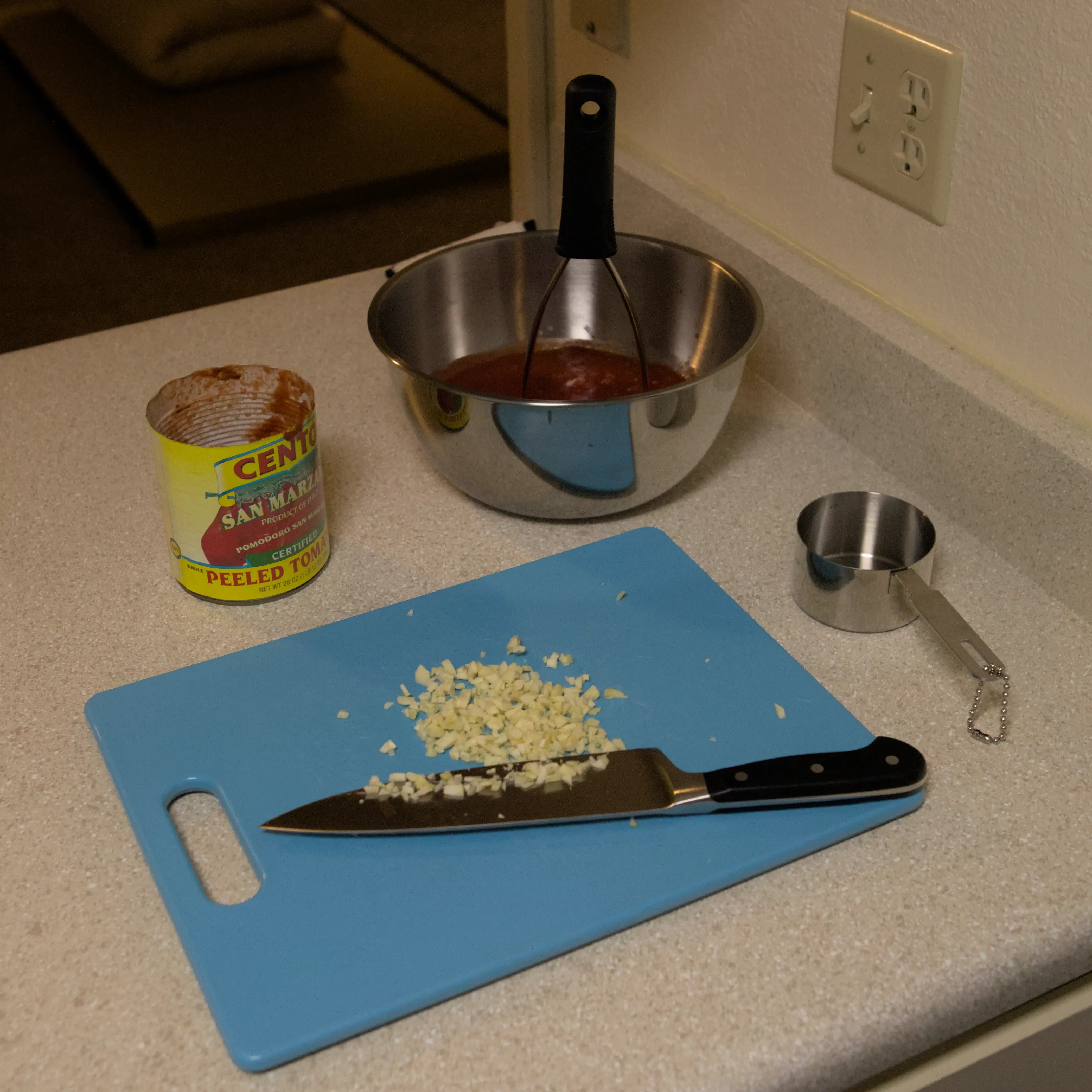 Mixing bowl with crushed tomatos, and cutting board with chopped garlic